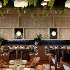 the interior of a restaurant with wooden tables and chairs, plants hanging from the ceiling