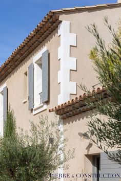 an old building with shutters and trees in front