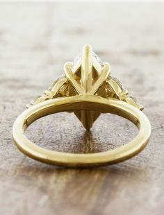 a yellow gold engagement ring with three diamonds on the side and an accent diamond in the center