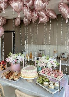 a table topped with lots of pink balloons and desserts on top of it's sides