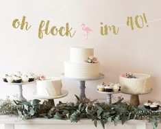 a table topped with cakes and cupcakes next to a sign that says custom banner