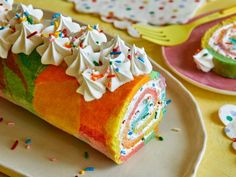 a colorful cake with white frosting and sprinkles sits on a plate