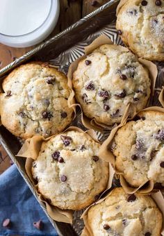 chocolate chip muffins on a tray next to a glass of milk and napkin