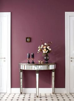 a table with flowers and candles on it in front of a wall painted purple, white and black