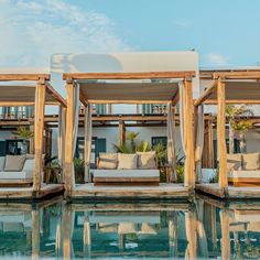 four wooden beds sitting next to each other on top of a swimming pool in front of a building