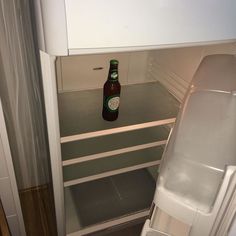 a beer bottle is sitting in an empty refrigerator