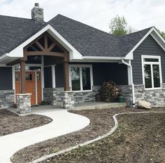 a gray house with white trim and wood accents on the front door is shown in this photo