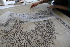 a woman is working on an art project with black and white ink in her hands