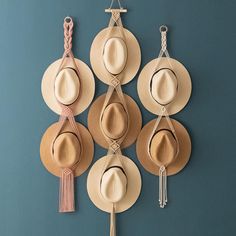 six hats hanging on the wall with tassels attached to each hat hanger