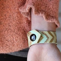 a person's hand with a bracelet on it that has a black stone in the center