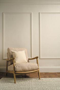 a chair sitting on top of a wooden floor next to a white wall with paneling