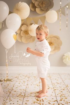 a little boy is standing in front of balloons and confetti on the floor