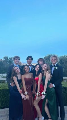 a group of young people standing next to each other in formal wear and tuxedos