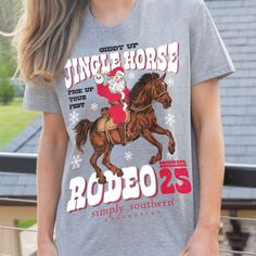 Celebrate the holiday season with a western twist in this playful Simply Southern tee! Featuring Santa riding a horse, this shirt brings the joy of Christmas to the rodeo with the fun phrase "Giddy Up Jingle Horse, Pick Up Your Feet. Rodeo December 25." Whether you're decking the halls or saddling up for a winter adventure, this tee adds a touch of country charm to your holiday wardrobe. Made from soft, breathable fabric, it's perfect for staying comfy and stylish all season long. Festive design Christmas Tee Shirts Western, Christmas Tshirts For Women Western, Trendy Short Sleeve Rodeo T-shirt, Simply Southern Tees, Casual Short Sleeve T-shirt With Horse Design, Southern Women, Simply Southern Dog Shirts, Simply Southern, Winter Adventure