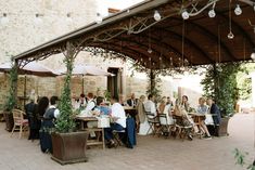 a group of people sitting at tables under an awning