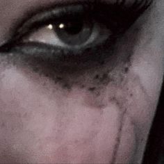 an evil looking woman's eye with black makeup