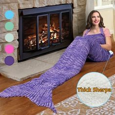 a woman laying on the floor next to a fireplace with a pink knitted mermaid tail