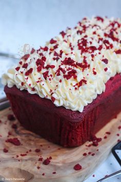 a piece of red velvet cake with white frosting and sprinkles on top