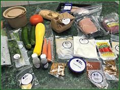 an assortment of vegetables and meats on a counter with plastic wrapper around them