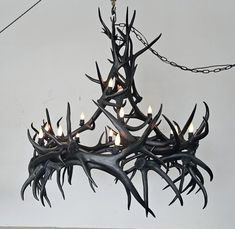 a chandelier with antlers hanging from it's sides and lit candles in the middle