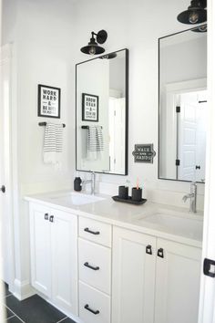 a white bathroom with two mirrors above the sinks and black accents on the wall behind it