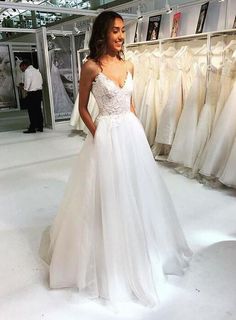 a woman standing in front of a rack of wedding dresses