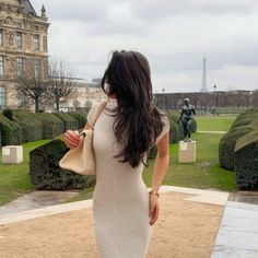 a woman in a white dress is standing outside