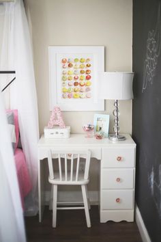 a white desk sitting next to a chalkboard in a bedroom under a window with curtains