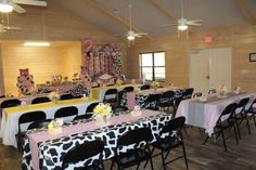 a room filled with tables and chairs covered in pink and black cow print cloths