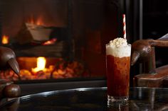 a drink sitting on top of a table next to a fire place