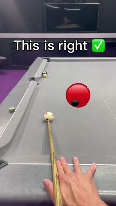 a hand is about to hit a pool ball with a cues in front of it