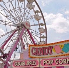 an amusement park with a ferris wheel and candy apples pop corn sign on the front