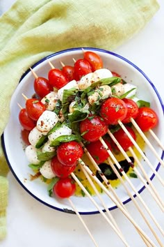 tomatoes, mozzarella and basil on skewers in a white bowl