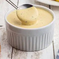 a spoon full of cheese sauce in a white bowl