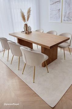 a dining room table with white chairs and a rug on the floor in front of it