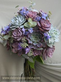 a bouquet of purple and green flowers in a vase