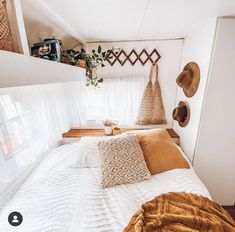 a bed in a small room with pillows and blankets on the bedspread next to a window