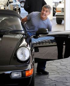 a man leaning on the hood of a black sports car