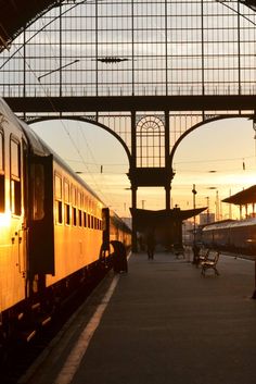 a train station with two trains parked next to each other and people walking on the platform