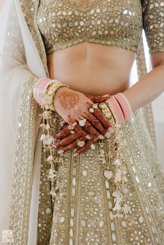 a woman in a bridal outfit holding her hands on her chest and wearing jewelry