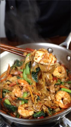 stir fry with shrimp and vegetables being stirred by chopsticks in a wok