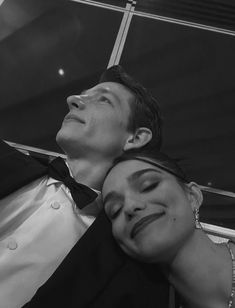 a man and woman are posing for a photo in front of a glass wall with their eyes closed