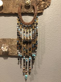 a necklace hanging on the wall next to a wooden hook with bead and glass beads