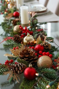 a christmas table runner with pine cones, ornaments and candles