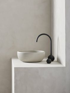 a white bowl sitting on top of a counter next to a black faucet