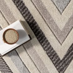 a bowl of grain on top of a white and black rug next to a box