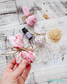 someone is holding some fabric wrapped balls with flowers on them and an essential oil bottle in the background