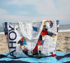 a large white bag sitting on top of a blue blanket near the ocean and sand