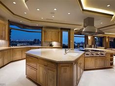 a large kitchen with wooden cabinets and an island in front of a window overlooking the city