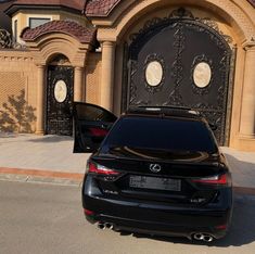 a black car is parked in front of a large building with ornate ironwork on it's doors